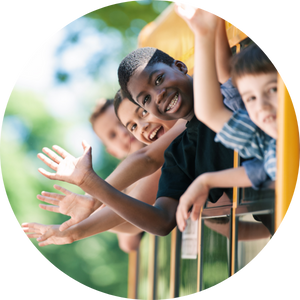  young students waving from school bus windows